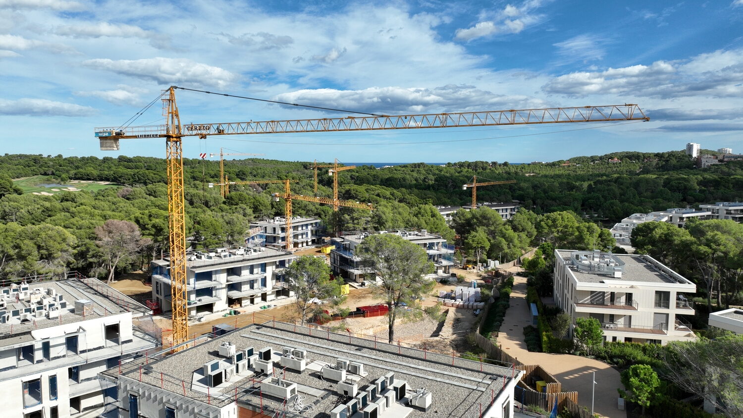 Grúas torre en una promoción residencial entre pinos