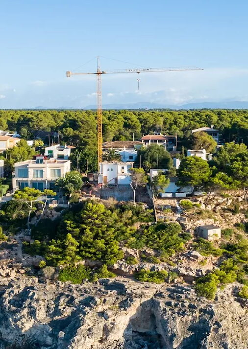 Grúa torre en una obra de viviendas junto a la costa de Menorca Grúa torre en una obra de viviendas junto a la costa de Menorca